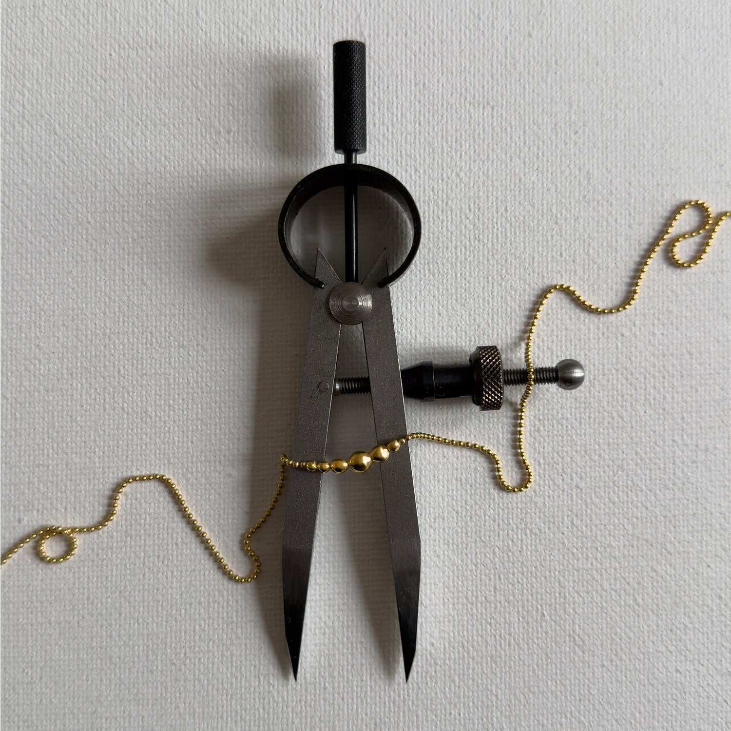 Black compass with gold chain on a light gray background