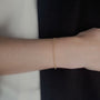 Gold circle bracelet on a person's wrist with a blurred background