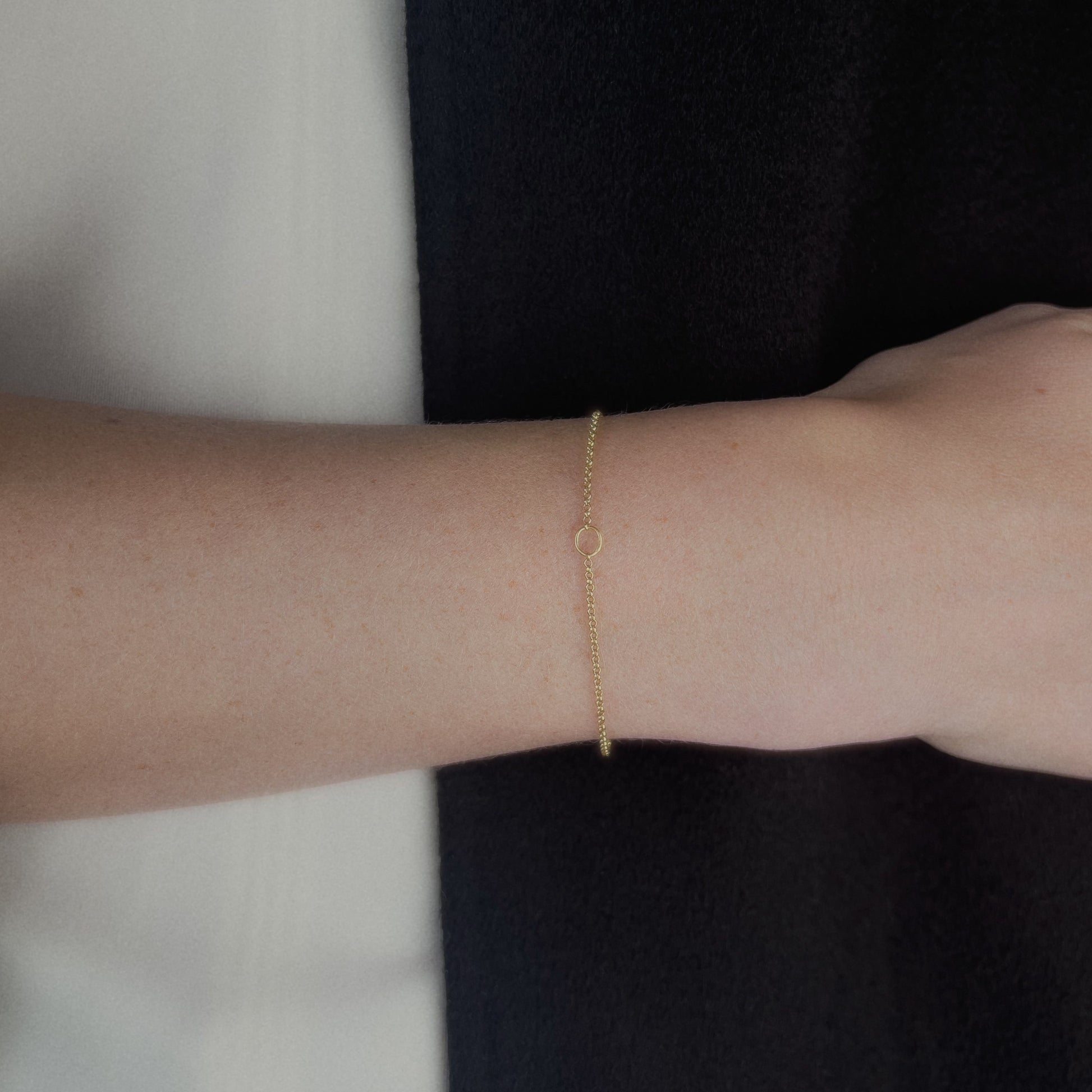 Gold circle bracelet on a person's wrist with a blurred background