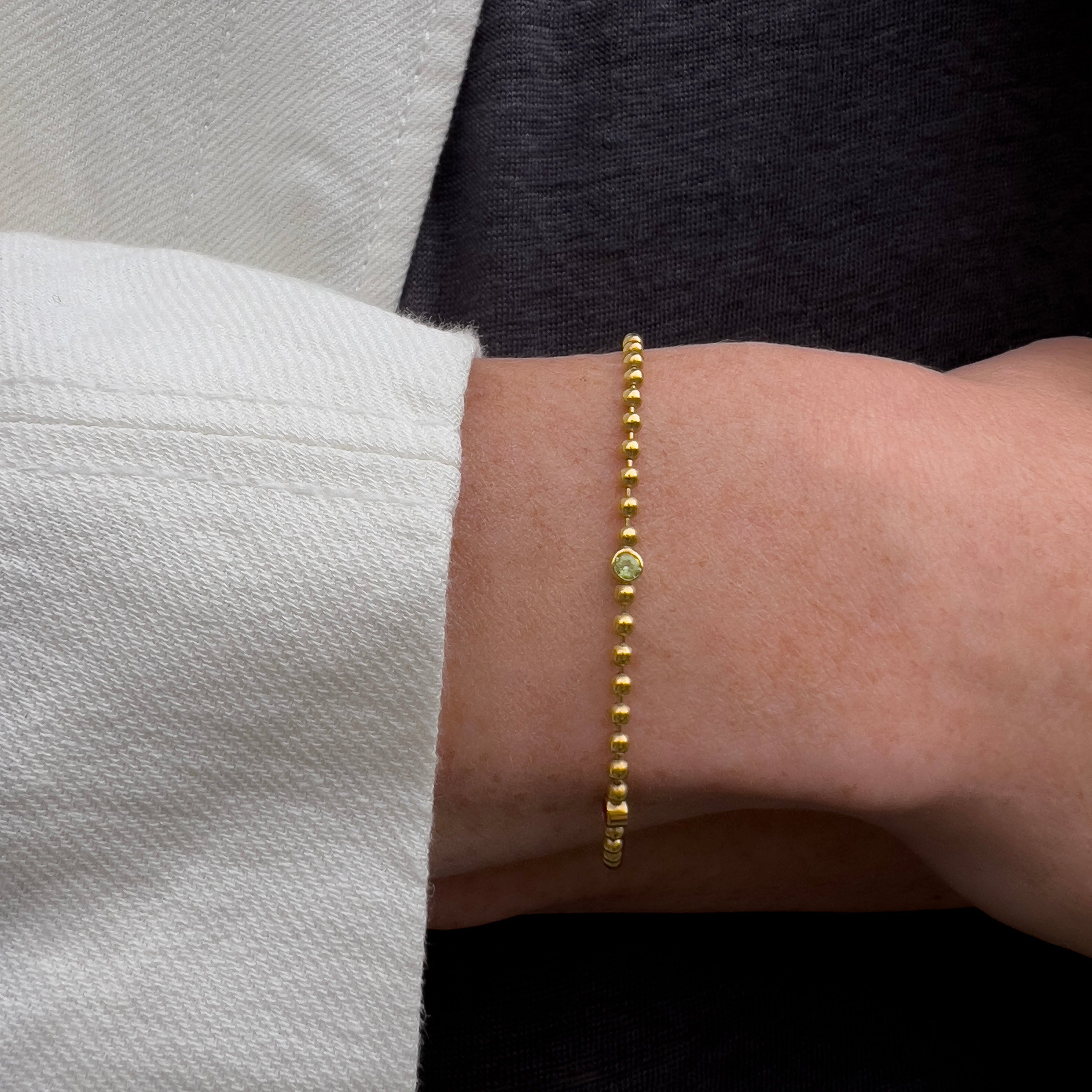 Gold bracelet on a wrist with a neutral background