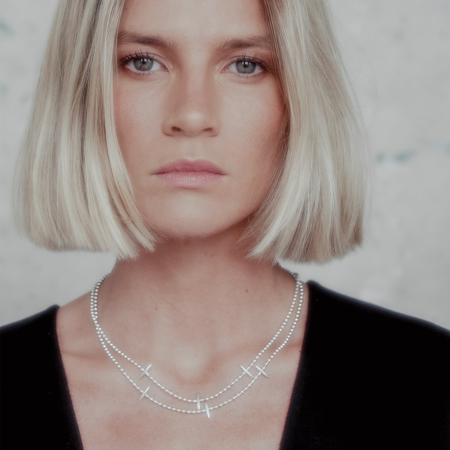 Woman wearing a silver spike necklace with a neutral background