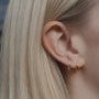 blonde woman wearing silver and gold curved stud earrings