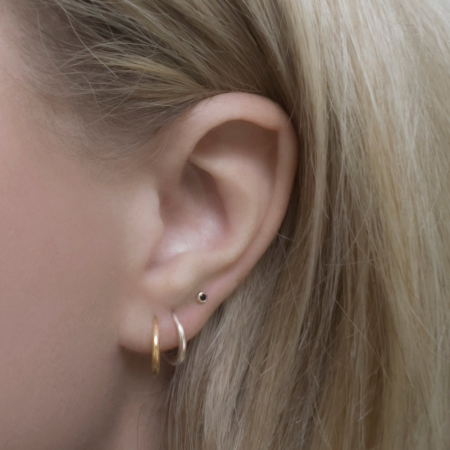 Gold and silver simple hoop earrings, with a black diamond stud.